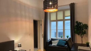 A modern bedroom with a bed, a desk, a sofa, and a large window with curtains. - Designer Apartment - 5 min to Center (Vienna)
