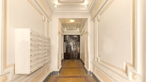 A hallway with a tiled floor, a wall-mounted mailbox, and a door at the end. - Designer Apartment - 5 min to Center (Vienna)