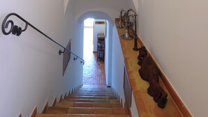 A staircase with a handrail, a wall with hanging guitars, and a view into an adjacent room.