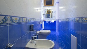 A bathroom with blue tiles, a toilet, a sink, and a mirror.