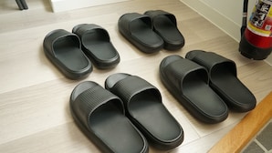 A set of black slippers arranged on a wooden floor. - Villa Feliz 101 (Naha)