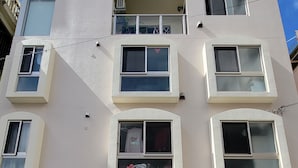 A modern multi-story building with a garage parking a white car. - Villa Feliz 101 (Naha)