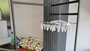 A kitchen with a metal drying rack, a sink, and a countertop with a patterned cloth. - Villa Feliz 101 (Naha)