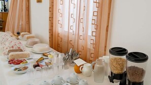 Ein reichhaltiges Frühstücksbuffet mit verschiedenen Speisen, Tee-Sets und einer Kaffeemaschine.