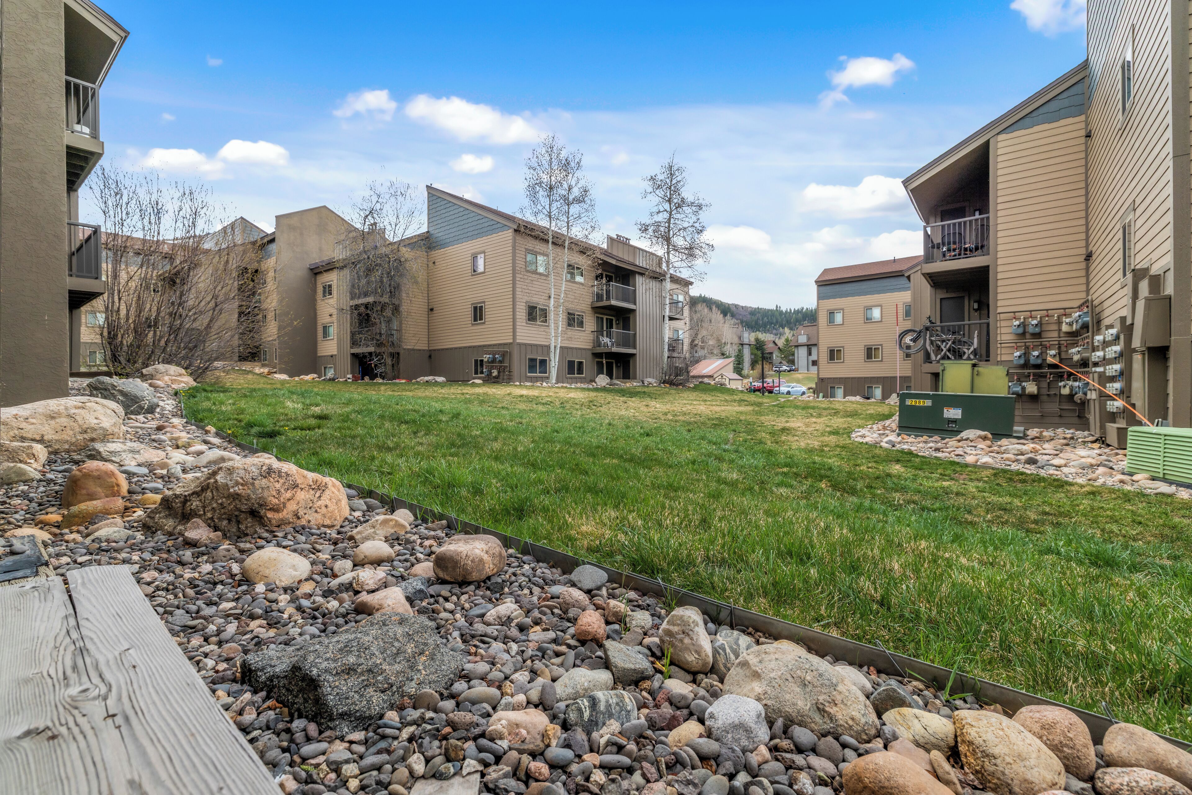 A residential complex with multiple apartment buildings, a grassy courtyard, and a wooden deck.
