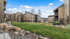 Un ensemble résidentiel comprenant plusieurs immeubles d’appartements, une cour verdoyante et une terrasse en bois.