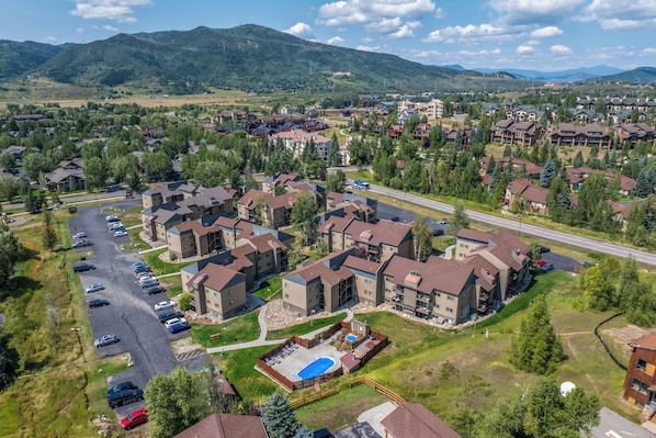 An aerial view of a residential area with multiple apartment buildings, a parking lot, and a swimming pool.