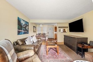 A living room with a sofa, coffee table, and a flat-screen TV mounted on the wall.