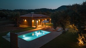 Una casa moderna con piscina, mobiliario exterior y vistas del paisaje circundante.