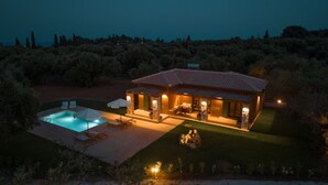 Una casa con piscina, mobiliario de exterior y un patio bien iluminado.