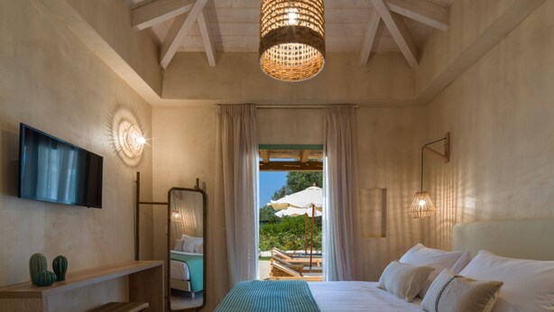 Un dormitorio con cama, televisión, espejo, banco y vistas al exterior.