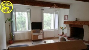 A living room with a sofa, TV, fireplace, and large windows. - Chez Makita - RdC (Mirepeisset)