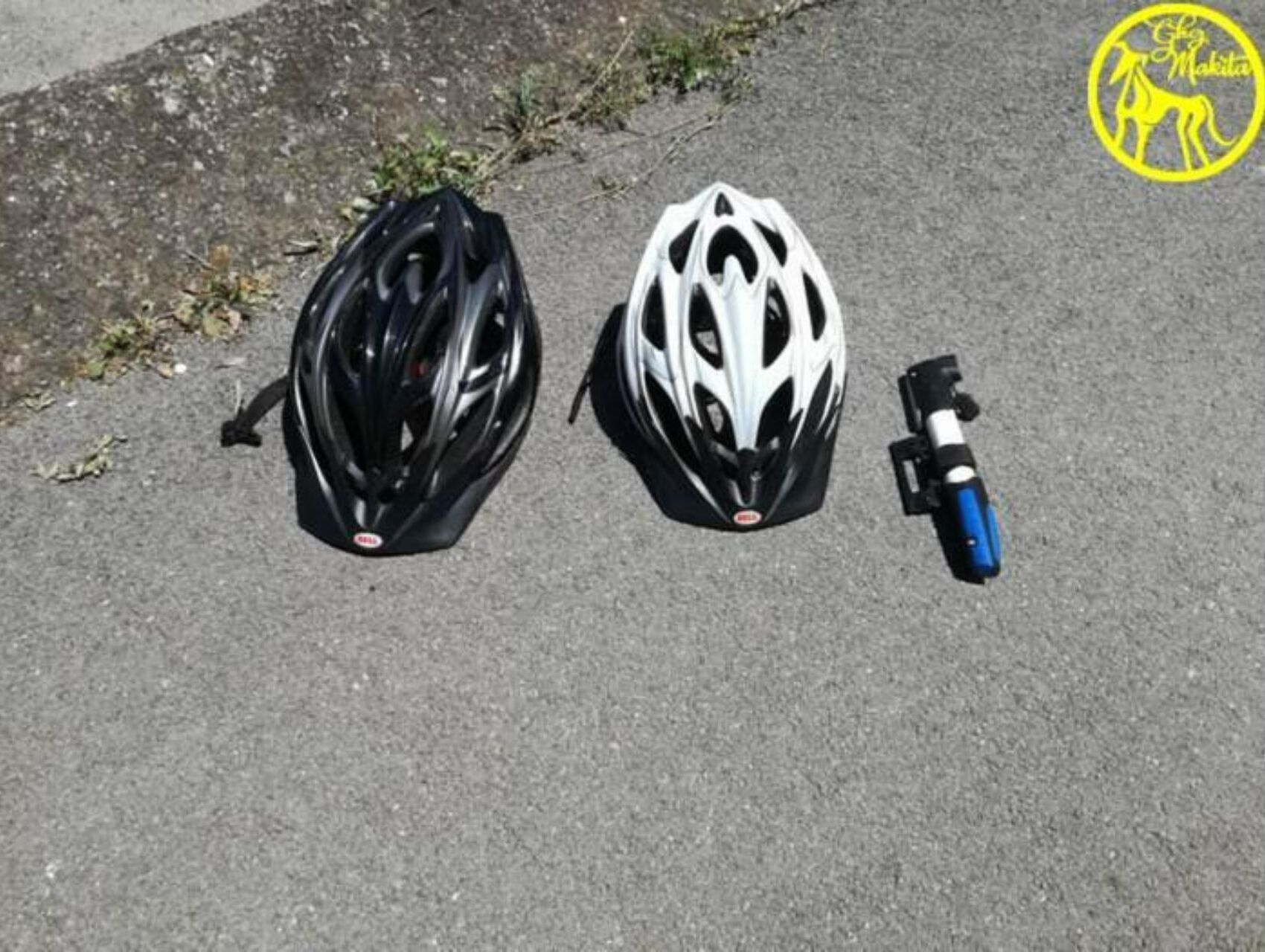 Two helmets and a water bottle on a paved surface.