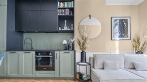 Una cocina moderna con horno integrado y zona de comedor con sofá y espejo redondo.