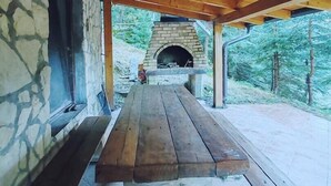 Un espacio de comedor al aire libre cubierto, con pared de piedra y horno de ladrillo.
