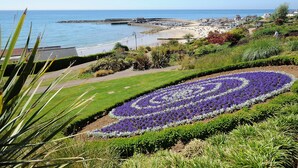 A coastal landscape with a flower garden, a beach, and a promenade. - Malabar House (Lyme Regis)