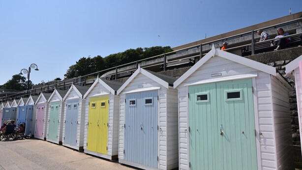 A row of colorful beach huts with white exteriors and doors in various pastel colors. - Malabar House (Lyme Regis)