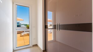 Un intérieur moderne avec une porte-fenêtre coulissante donnant sur un espace extérieur doté d’une terrasse en bois et de parasols.