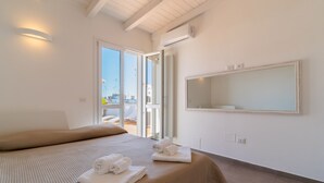 Une chambre d’hôtel avec un grand lit, un balcon avec vue et un miroir au mur.
