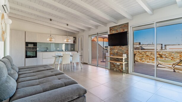 Un espace de vie moderne comprenant un canapé, un coin repas, une cuisine et un balcon avec vue.