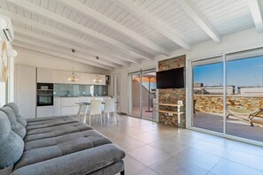 Un espace de vie moderne comprenant un canapé, un coin repas, une cuisine et un balcon avec vue.
