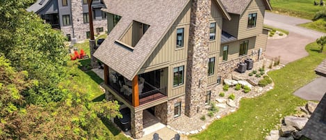A multi-story building with a stone facade, multiple balconies, and a landscaped outdoor seating area with chairs and a fire pit.