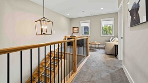 A staircase with wooden steps and black railings, leading to a living area with a sofa and a coffee table.