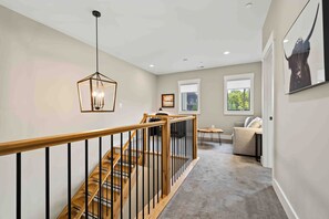 A staircase with wooden steps and black railings, leading to a living area with a sofa and a coffee table. - Mountain Mindset by Taylor Made Deep Creek (McHenry)