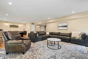A spacious living room with a sectional sofa, a leather armchair, and a coffee table. - Mountain Mindset by Taylor Made Deep Creek (McHenry)