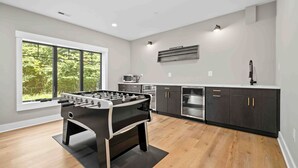 A modern kitchen with a foosball table, large windows, and built-in appliances.