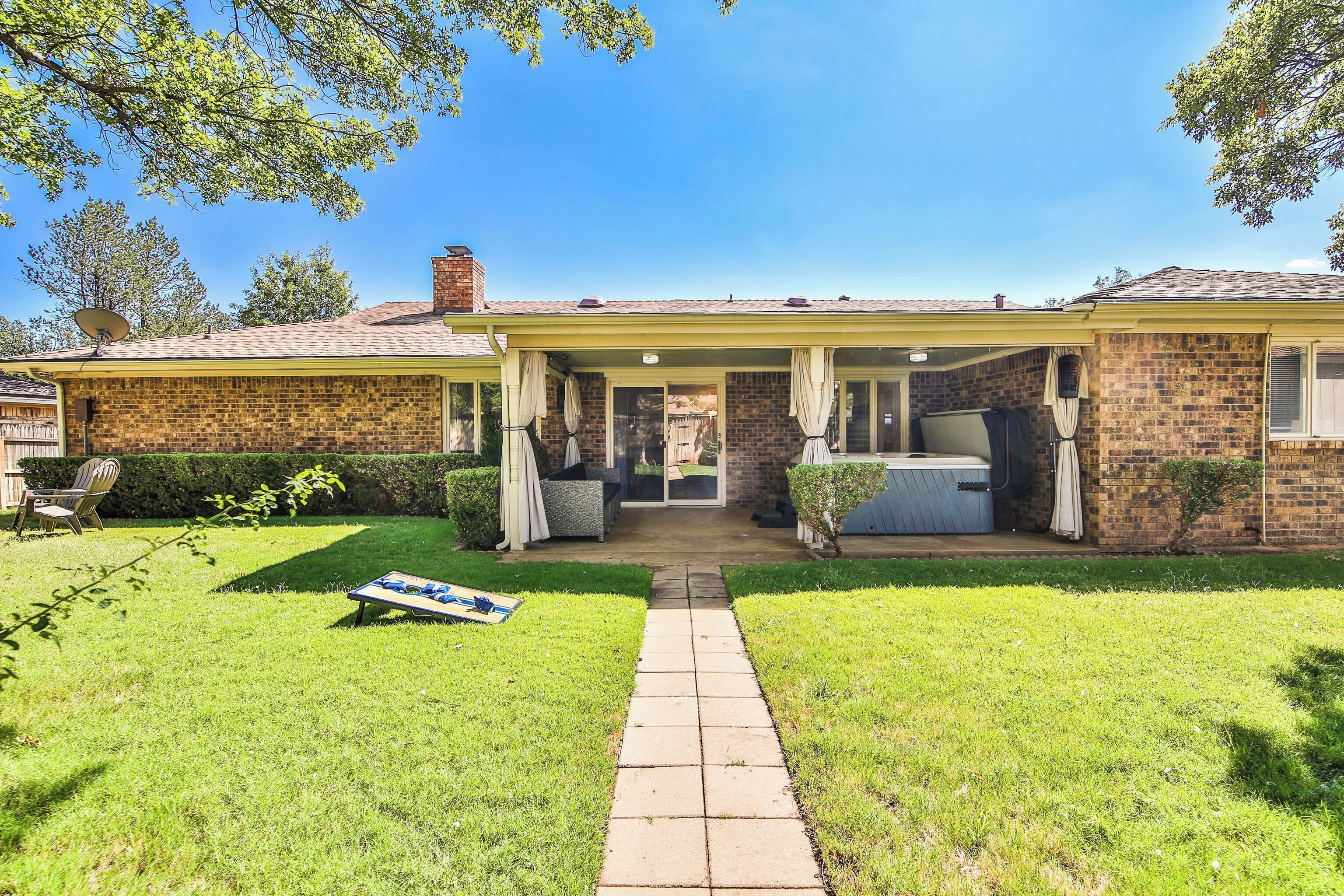 A two-story brick house with a covered patio, a satellite dish, and a small garden.