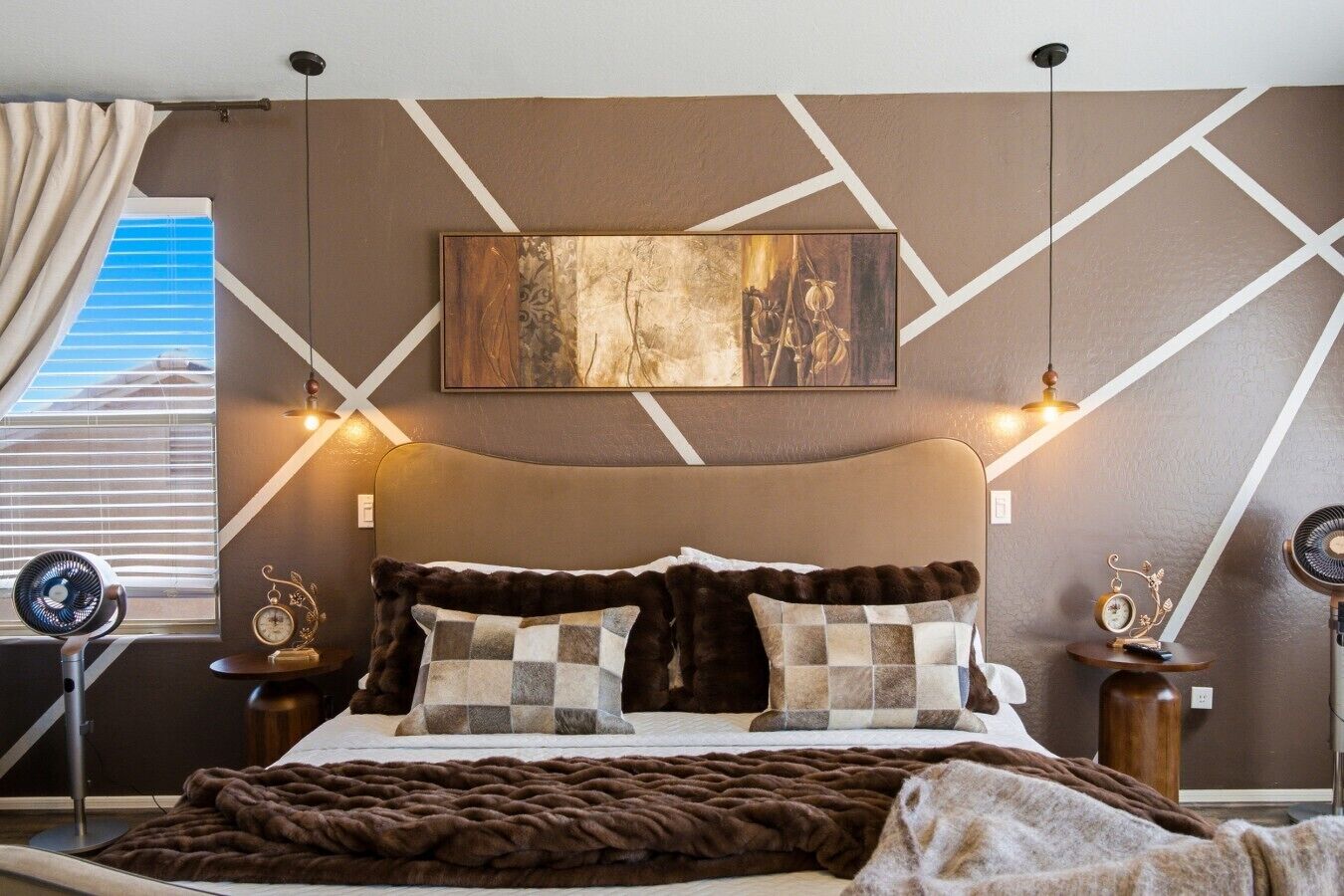 A modern bedroom with a large bed, decorative pillows, a mounted artwork, and bedside lamps.