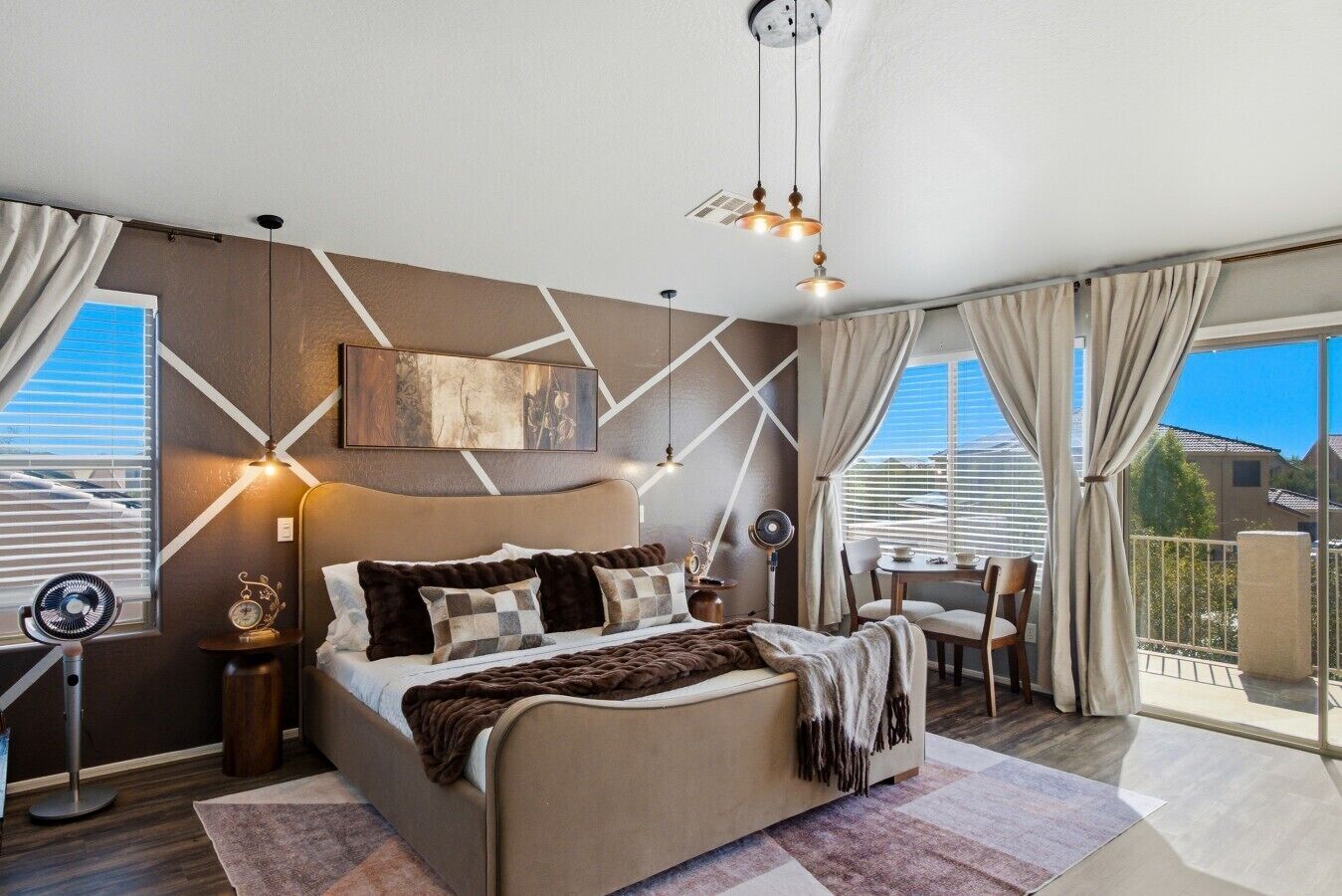 Une chambre moderne avec un grand lit, des tables de chevet, un bureau et un balcon avec vue.