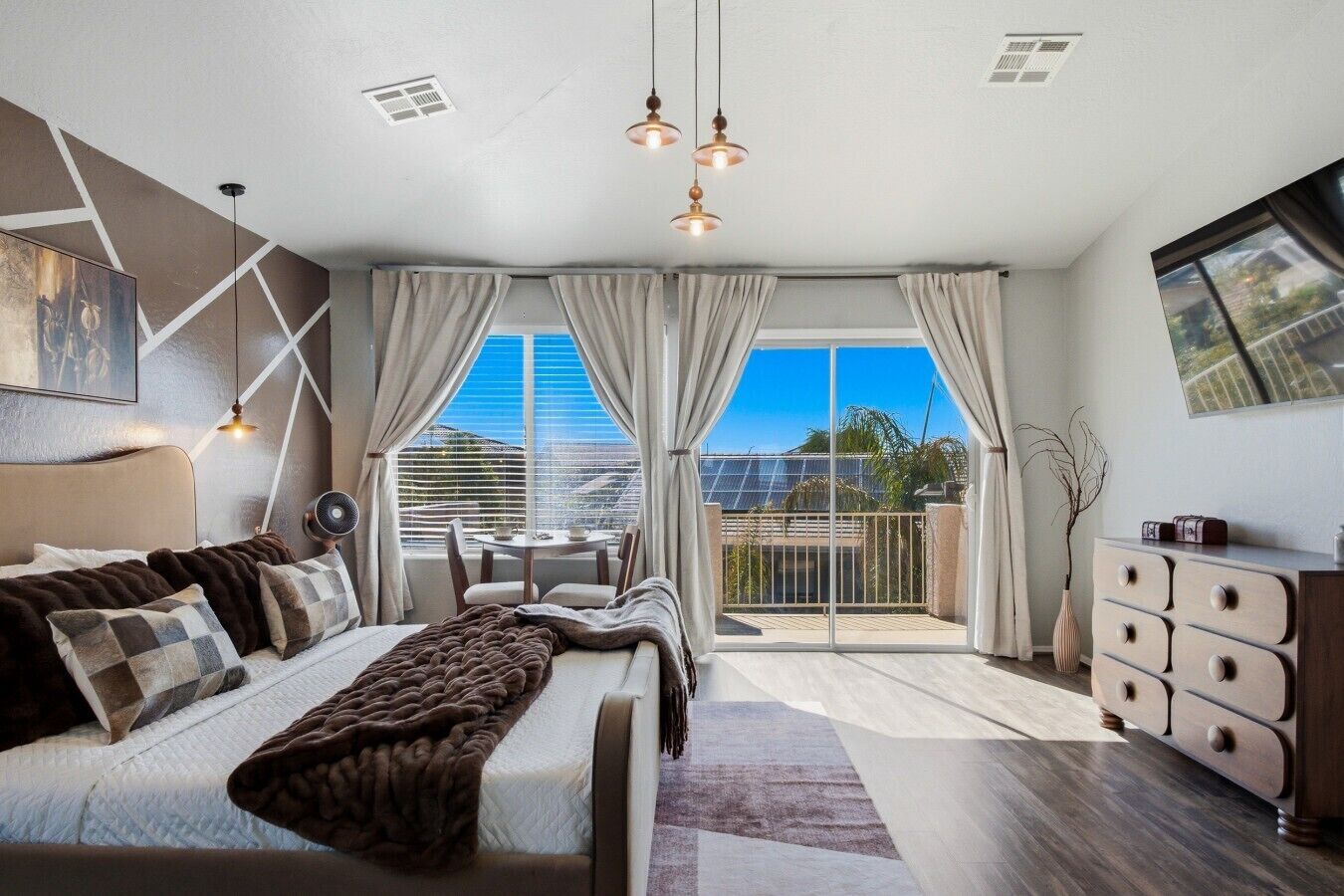 Een moderne slaapkamer met een bed, een zithoek, een balkon en een mooi uitzicht, en een dressoir.