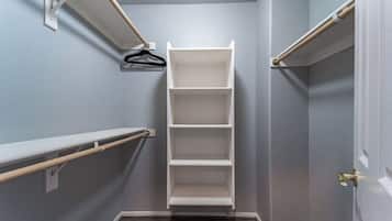 Un dressing avec des étagères blanches et une tringle pour suspendre les vêtements.