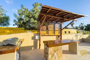 An outdoor patio area with a stone bench, a grill, and a wooden pergola structure. - Oceanfront Escape: Pool, BBQ, & Sunset Views (El Centenario)