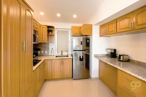 A modern kitchen with wooden cabinets, stainless steel appliances, and granite countertops. - Oceanfront Escape: Pool, BBQ, & Sunset Views (El Centenario)