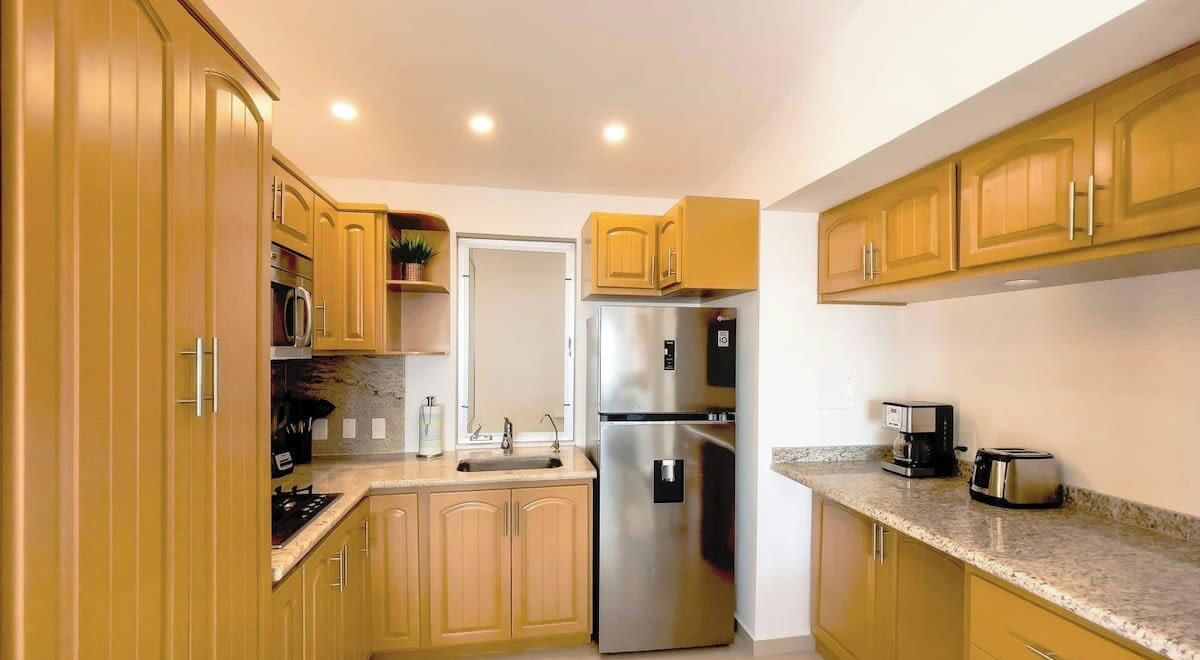 Une cuisine moderne avec des meubles en bois, des appareils en acier inoxydable et des plans de travail en granit.