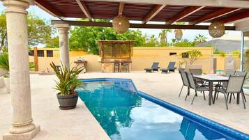 Ein Swimmingpool mit einer Pergola, Liegestühlen und einer Bar.