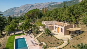 A villa with a swimming pool, surrounded by a landscaped garden and a view of mountains.