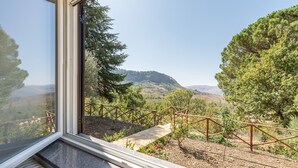 A room with a large window overlooking a garden with a wooden fence and a stone pathway.