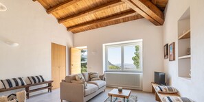 Un amplio espacio de sala con un alto techo de madera, un sofá, una mesa de centro y un banco.