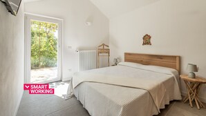 Een slaapkamer met een bed, nachtkastjes, een radiator en uitzicht op groen.