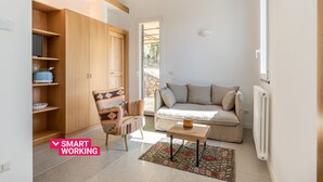 A modern living room with a sofa, a patterned armchair, a wooden cabinet, and a small table. - Borgo Le Niche by Wonderful Italy - Calliope (Polizzi Generosa)
