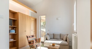 A modern living room with a sofa, a patterned armchair, a wooden cabinet, and a small table.