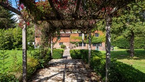 A stone pathway leading to a brick building with a garden and a pergola. - Gildridge Estat Large Group Tennis Court (Lewes)