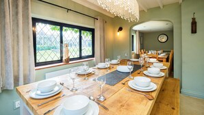 A dining area with a long wooden table set for a meal, a chandelier, and a view through a window. - Gildridge Estat Large Group Tennis Court (Lewes)
