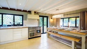 A modern kitchen with a large island, built-in oven, and a dining area with a bench. - Gildridge Estat Large Group Tennis Court (Lewes)