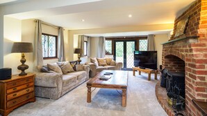 A spacious living room with a fireplace, a sofa set, a coffee table, and a television. - Gildridge Estat Large Group Tennis Court (Lewes)