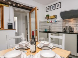 Une cuisine moderne avec des meubles blancs, un plan de travail noir et une table à manger dressée pour six personnes, avec assiettes, verres et couverts.